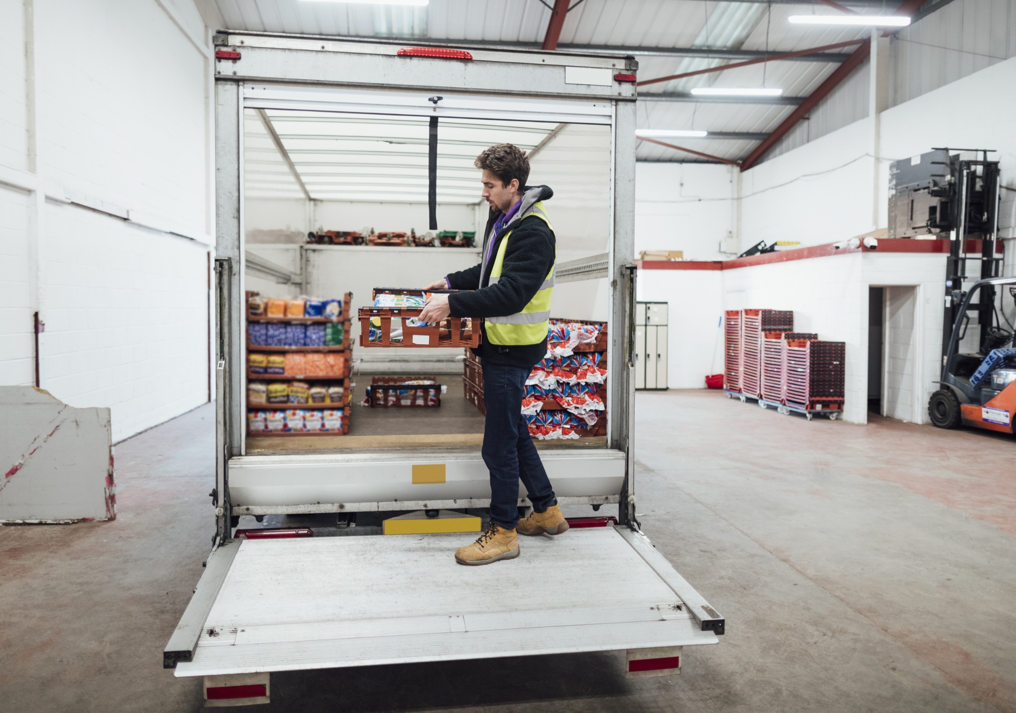 Warehouse worker loading a reefer truck with packaged food products for shipment