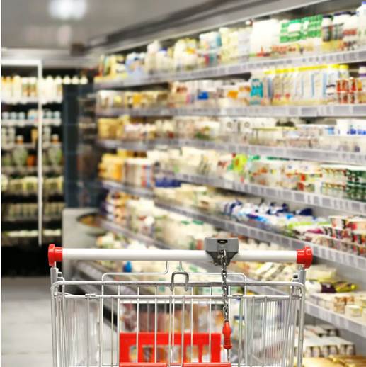 Two people standing in a grocery store, examining and discussing details on a clipboard next to a display of fresh lettuce in wooden crates.